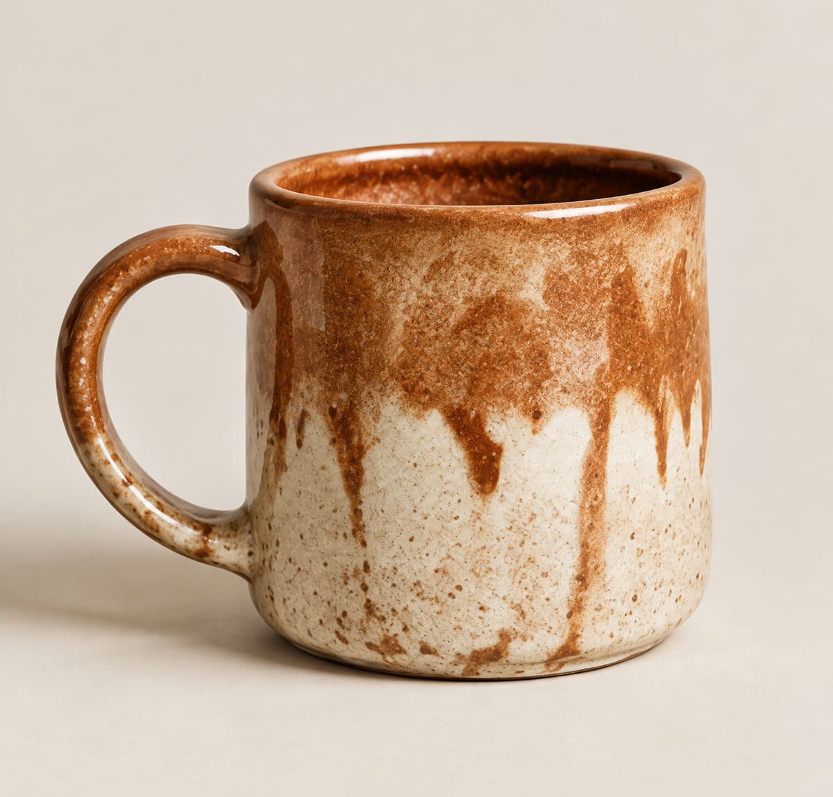 Handmade mug with rust-orange glaze dripping over cream clay
